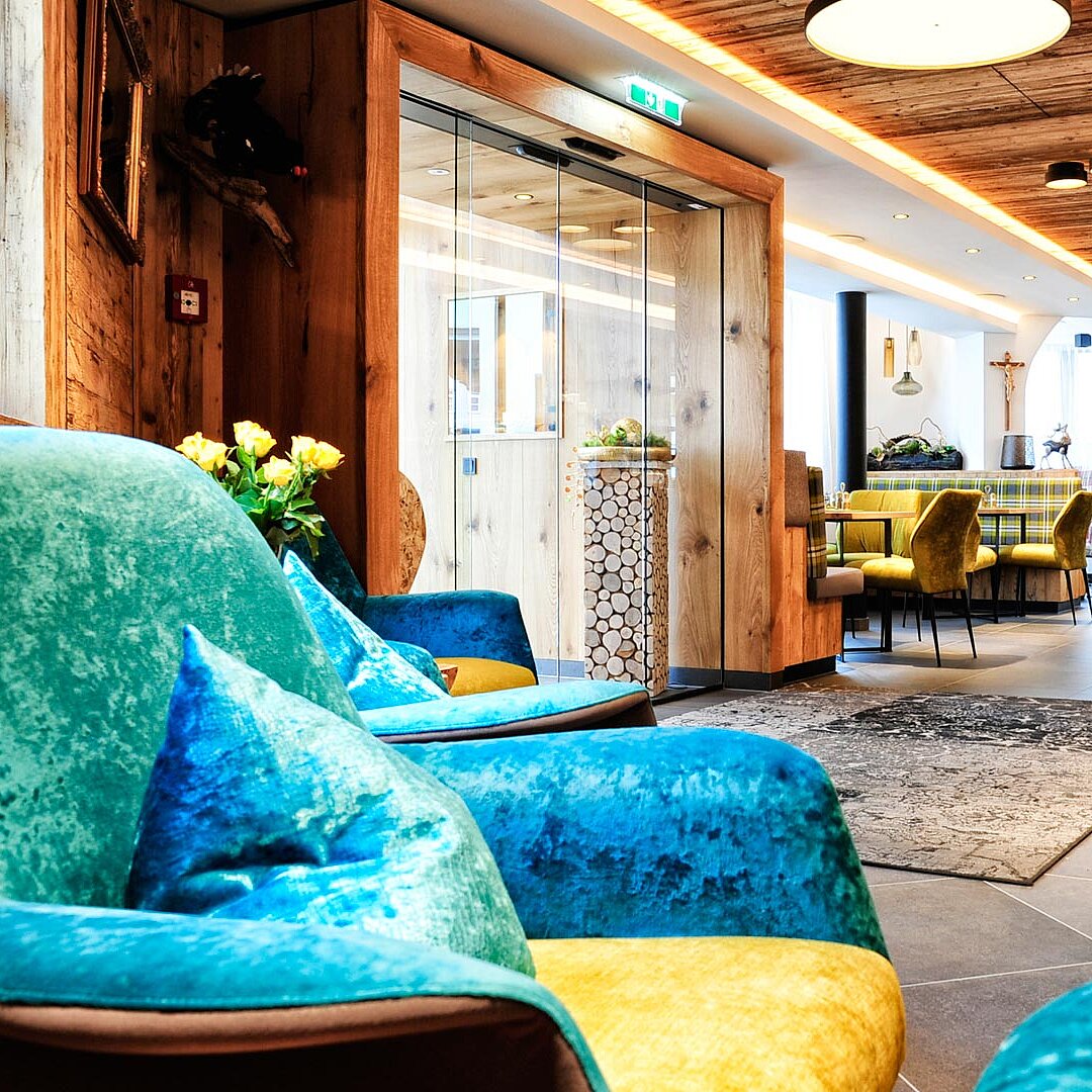 Moderne Lounge mit bunten Sesseln, Holzelementen, Bartresen, gemütlicher Beleuchtung und alpenländischem Designmix.